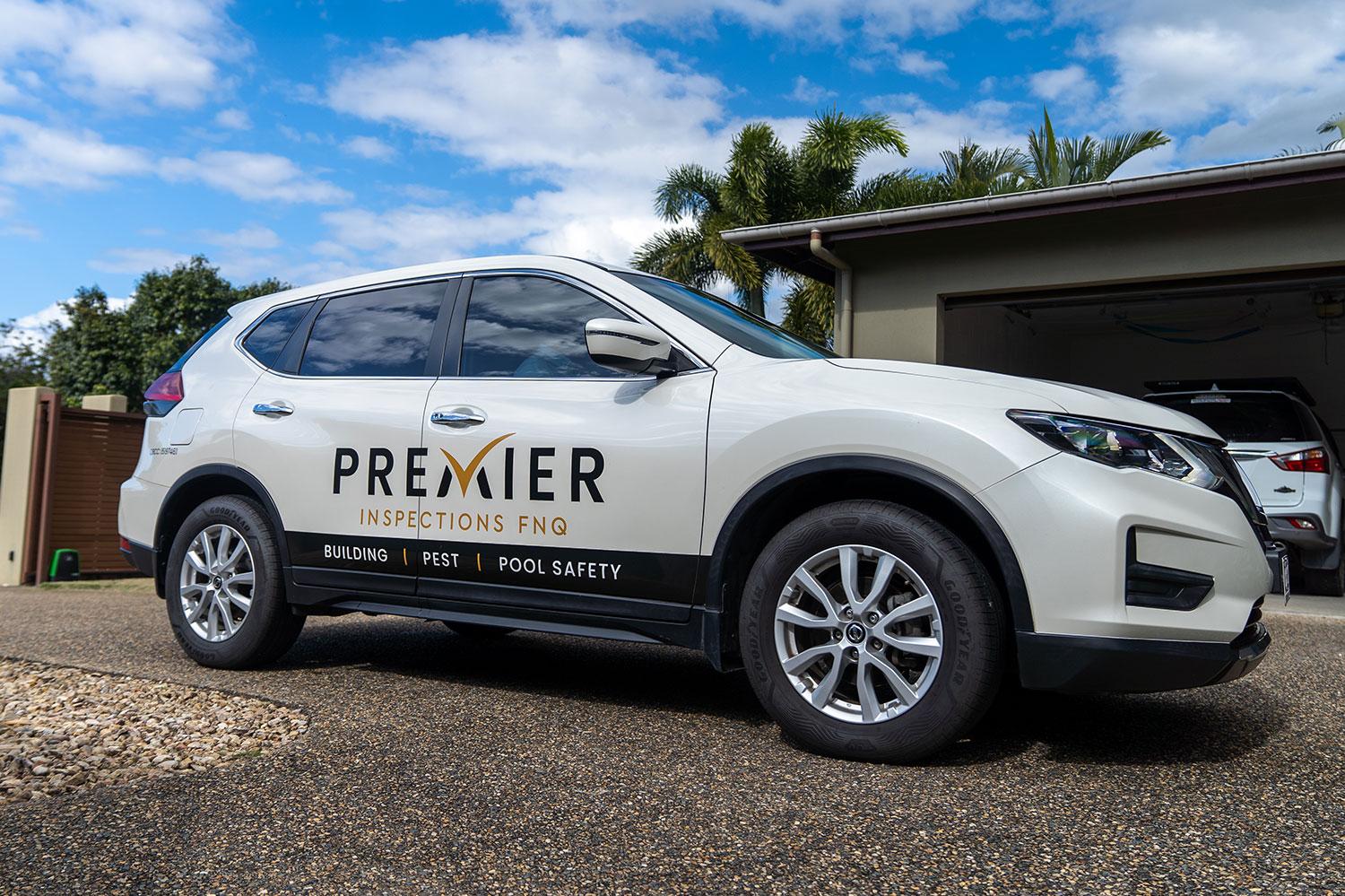 White Premier Inspections FNQ vehicle with building, pest, and pool safety services branding.